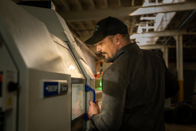 Craftsman operating precision machinery to create USA made EDC tools in a workshop setting