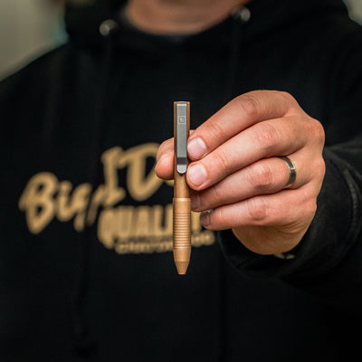 Close-up of a hand holding a bronze EDC pen made in USA with a clip, from BIGiDESIGN-USA