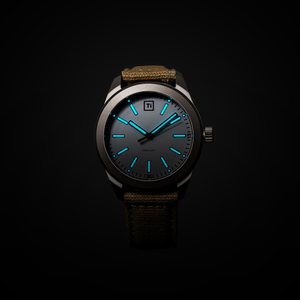 Big Idea Design LLC titanium field watch with luminous blue hands and markers dark dial titanium case canvas strap