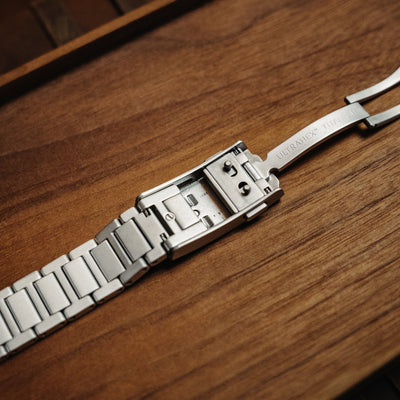 Close-up of silver premium titanium bracelet clasp on wooden surface by BIG IDEA DESIGN LLC