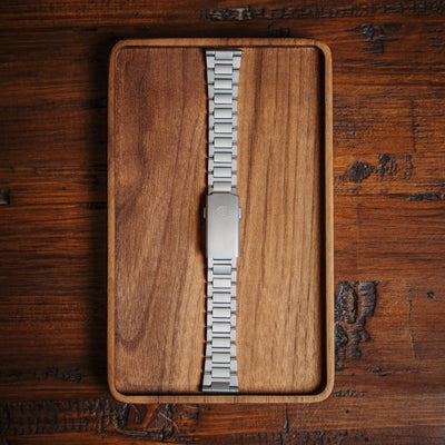 Silver premium titanium bracelet with polished links displayed on a wooden tray by BIG IDEA DESIGN LLC