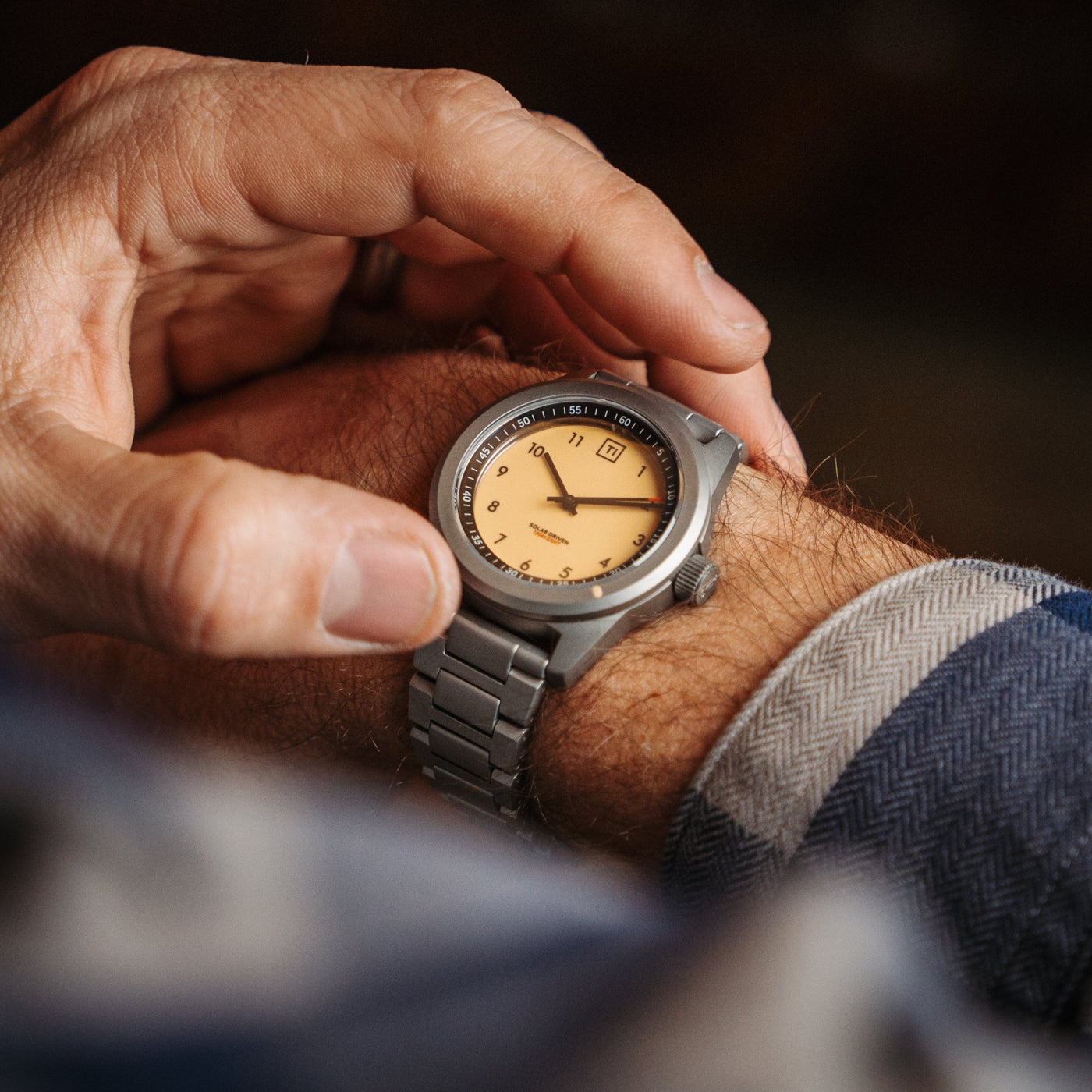 Man wearing a premium titanium bracelet watch with a beige dial and metal strap on wrist