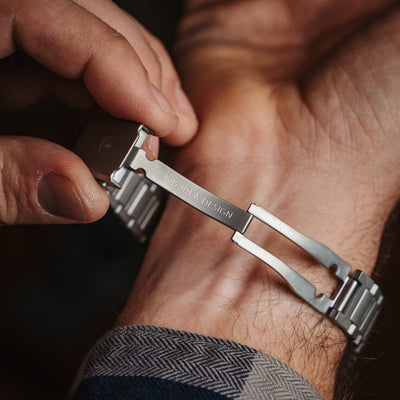Close-up of a hand fastening a premium titanium bracelet with BIG IDEA DESIGN engraving