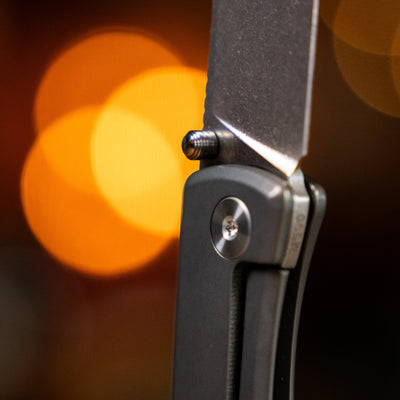 Close-up of titanium pocket knife blade and handle with textured grip and thumb stud