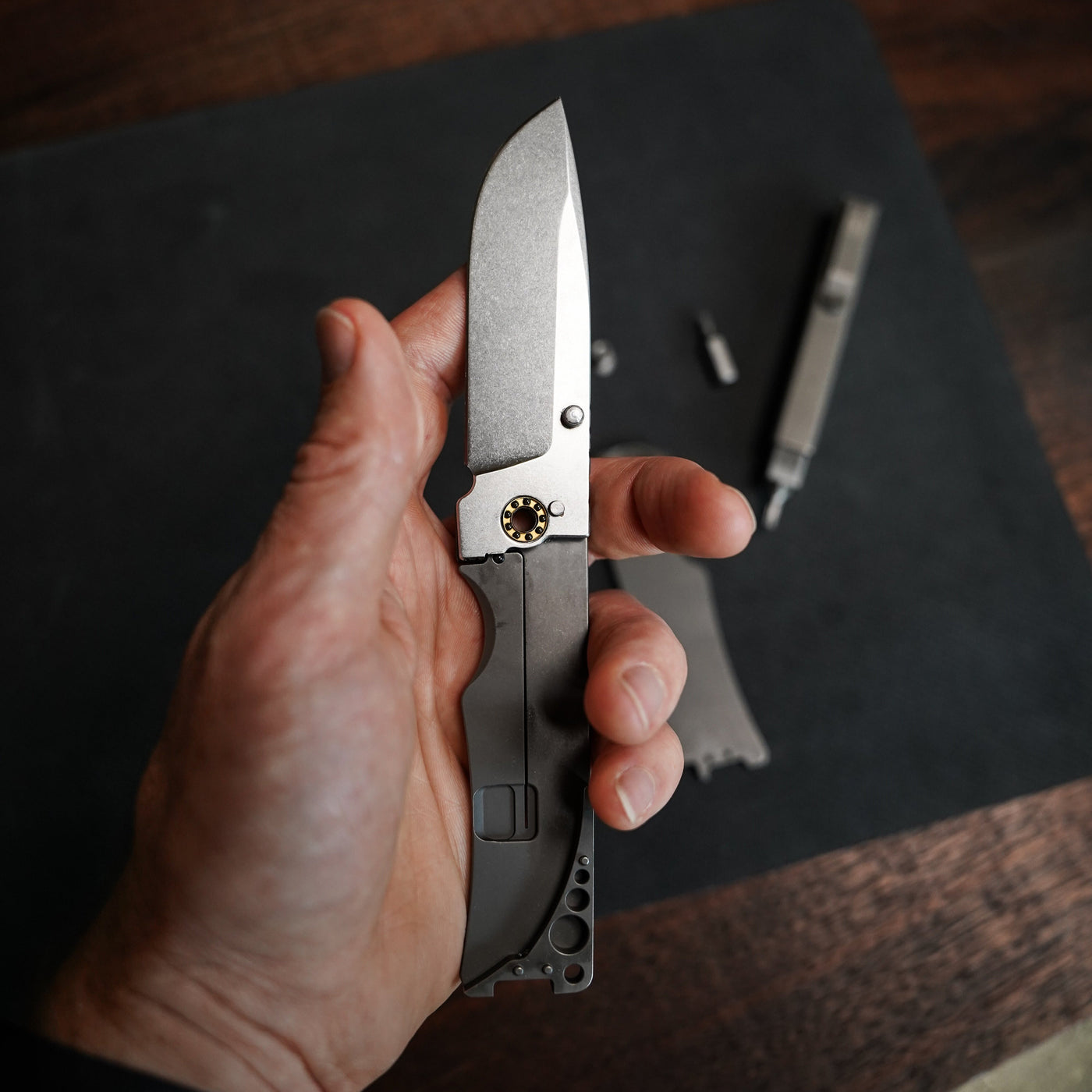 Hand holding a BIG IDEA DESIGN LLC titanium pocket knife with a sleek metal blade and ergonomic handle
