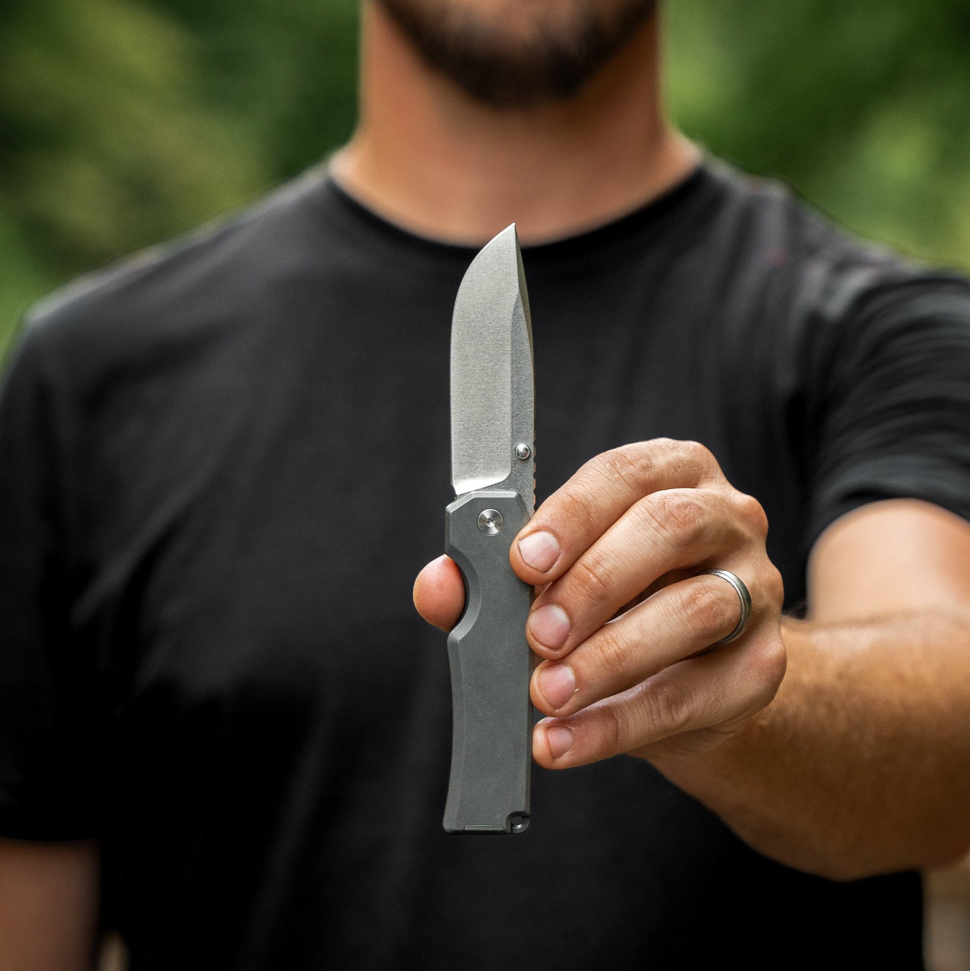 Man holding a titanium pocket knife by BIG IDEA DESIGN LLC with a stonewashed blade and sleek handle