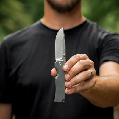 Man holding a titanium pocket knife by BIG IDEA DESIGN LLC with a stonewashed blade and sleek handle