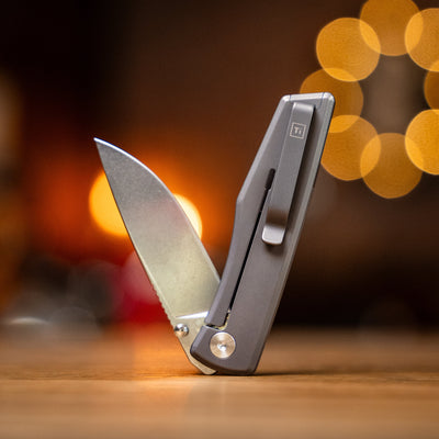 Big Idea Design LLC titanium pocket knife with sleek metal handle and sharp blade open on wooden surface