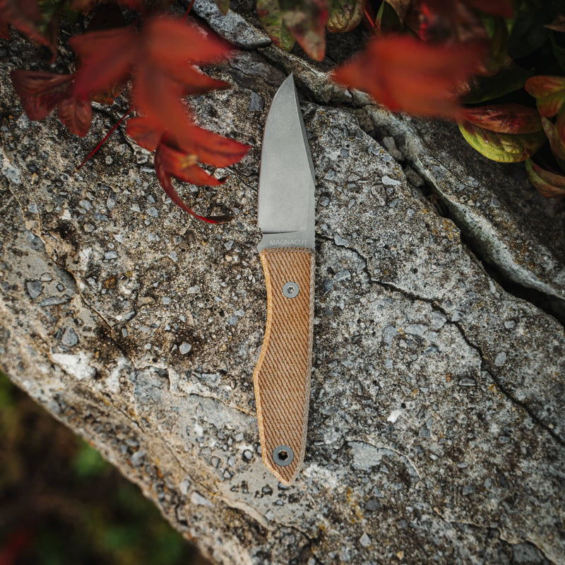 USA lookout fixed blade knife with textured tan handle resting on a textured rock surface outdoors