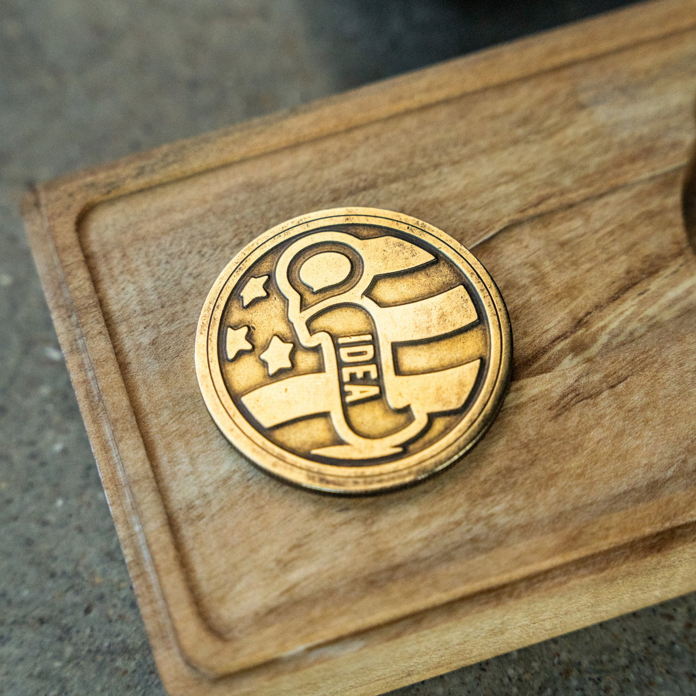 BIGiDESIGN-USA USA Lookout Fixed Blade knife logo brass emblem on wooden surface