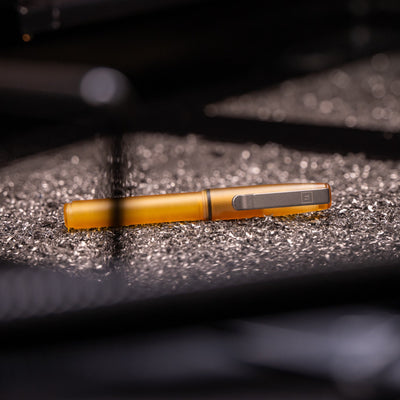 BIGiDESIGN-USA amber USA made EDC pen with metal clip on textured surface