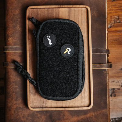 Black EDC pocket pouch by Big Idea Design LLC with zipper and patch details on wooden tray