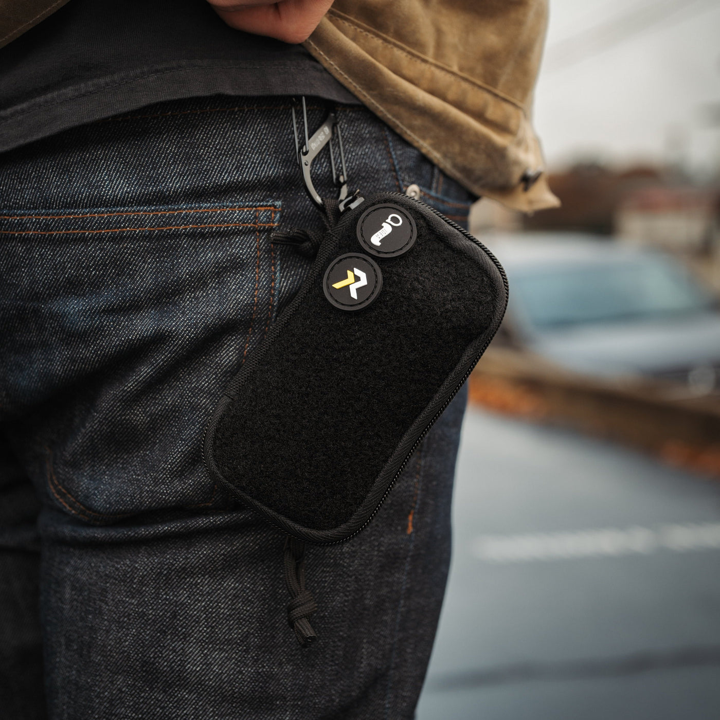 Black EDC pocket pouch clipped to blue jeans pocket for everyday carry convenience