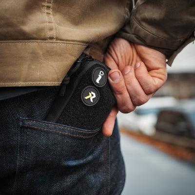 Black EDC pocket pouch by Big Idea Design LLC carried in back jeans pocket with zipper and patches