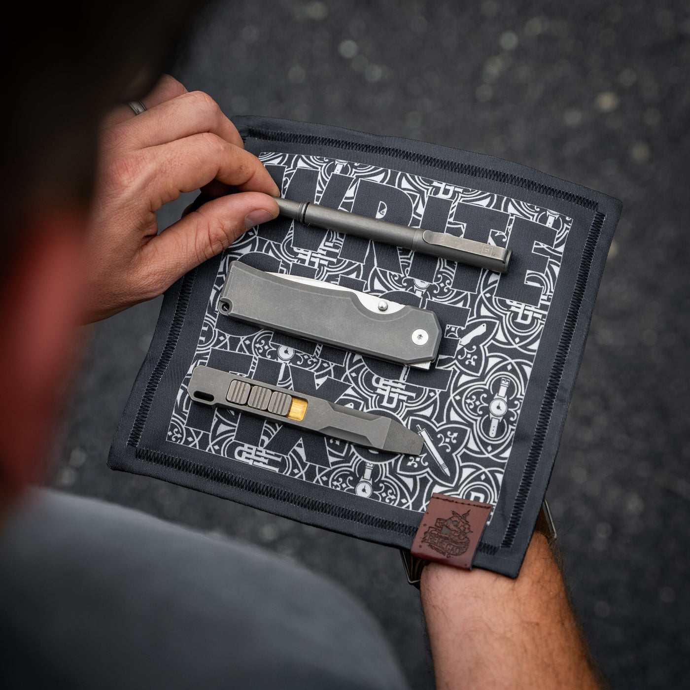Write Slice Fix Hank accessory featuring a pen and multi-tool on a patterned cloth by BIG IDEA DESIGN LLC