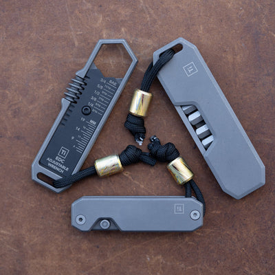 Big Idea Design LLC tools set with Damascus lanyard bead attached to black cords on gray metal tools