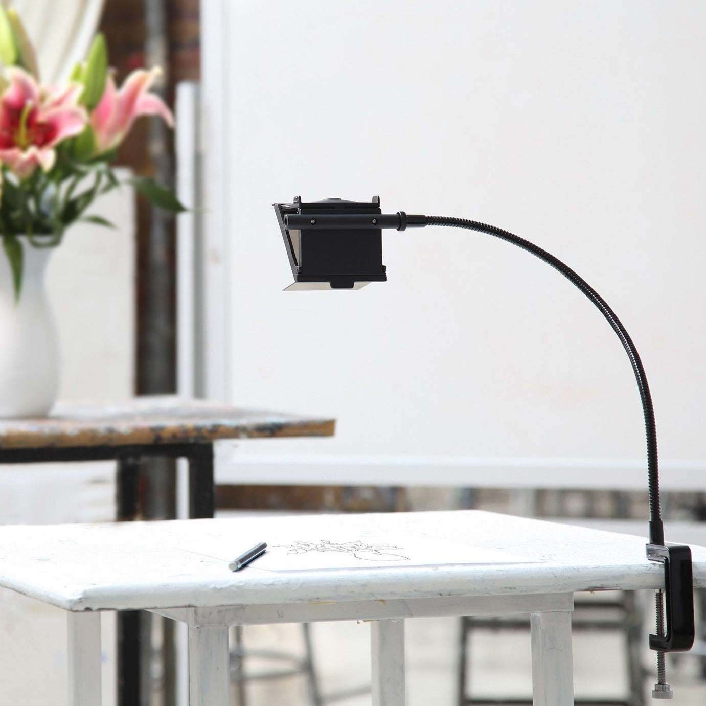 NeoLucida XL camera lucida drawing aid by BIG IDEA DESIGN LLC mounted on a white table with a flower vase in background