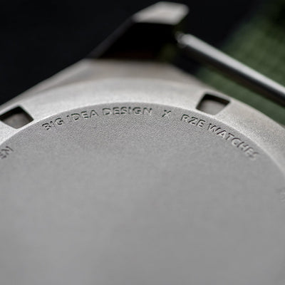 Close-up of solar titanium field watch back engraved with Big Idea Design and RZE Watches logos
