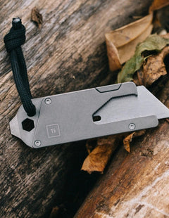 Titanium Pocket Tool EDC with a folding blade and black lanyard on a wooden surface