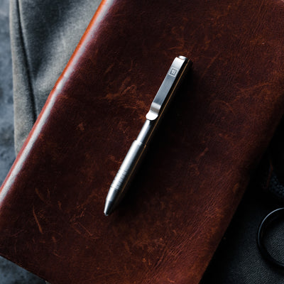 BIG IDEA DESIGN LLC stainless steel Pens on brown leather notebook with metal clip and textured background