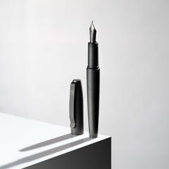 Big Idea Design LLC sleek black Titanium Fountain Pen with cap standing on white surface