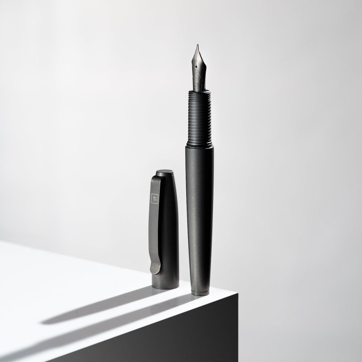 Big Idea Design LLC sleek black Titanium Fountain Pen with cap standing on white surface