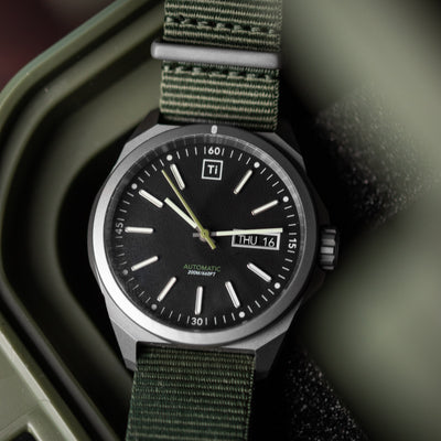 Big Idea Design LLC titanium automatic field watch with black dial and green fabric strap