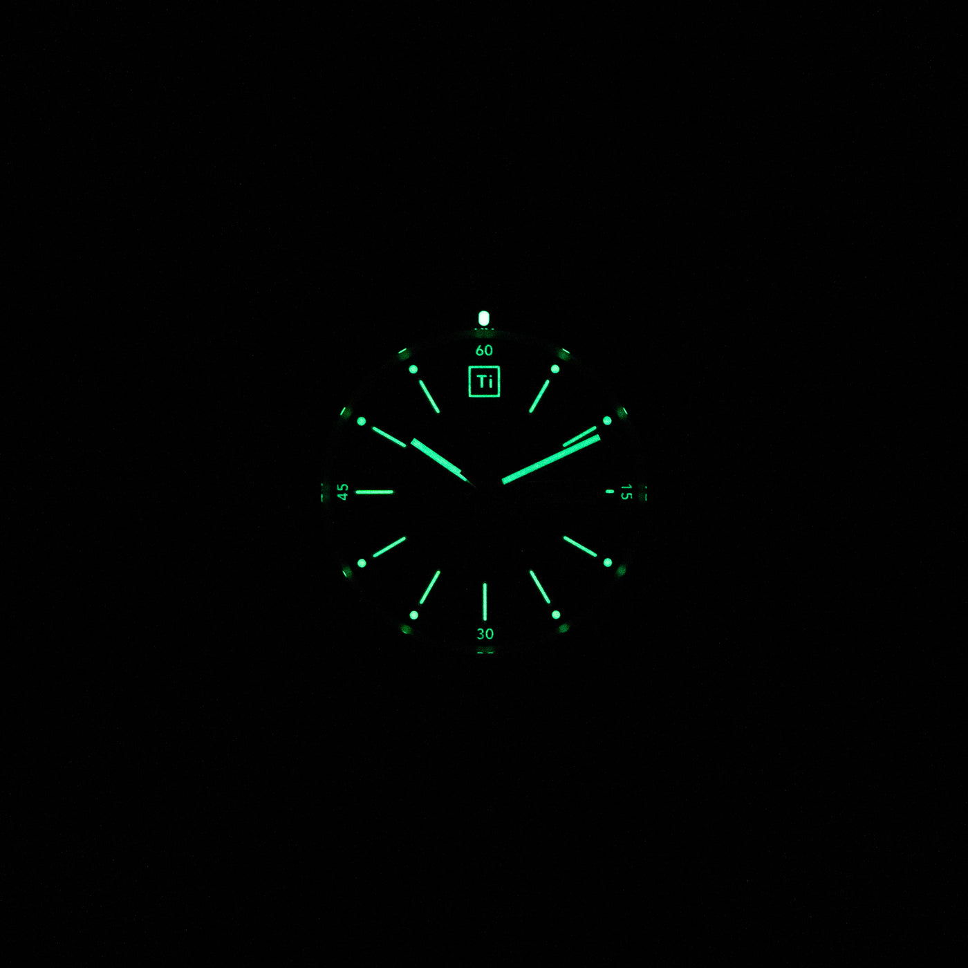 Luminous dial of titanium automatic field watch glowing green in dark by Big Idea Design LLC