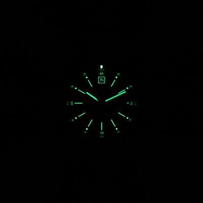 Luminous dial of titanium automatic field watch glowing green in dark by Big Idea Design LLC