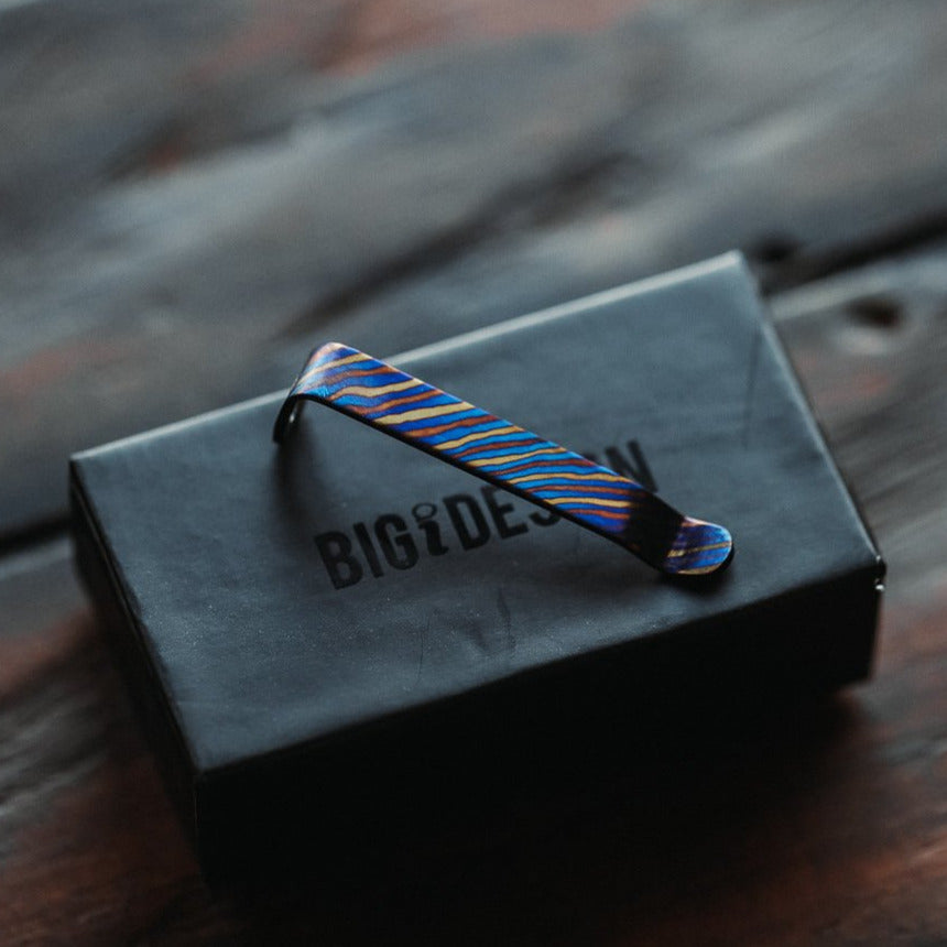 Titanium Damascus pen clip with vibrant blue and gold pattern on Big Idea Design LLC black box