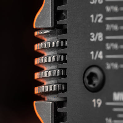 Close-up of titanium EDC wrench gear teeth and measurement markings on black metal surface