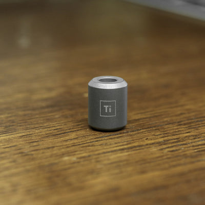 BIG IDEA DESIGN LLC titanium lanyard bead in gray metal with chemical symbol Ti on wood surface