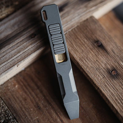 Big Idea Design LLC titanium pry bar tool in gray with textured grip on wooden surface