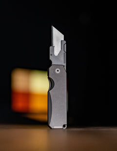 Big Idea Design LLC titanium utility knife with sleek metal handle and sharp blade standing upright