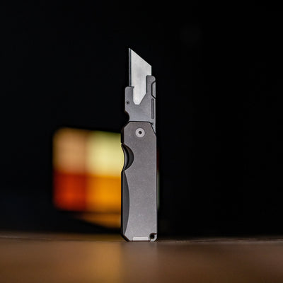 Big Idea Design LLC titanium utility knife with sleek metal handle and sharp blade standing upright