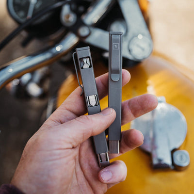 Person holding two sleek titanium screwdriver set tools with metal clips for precision work